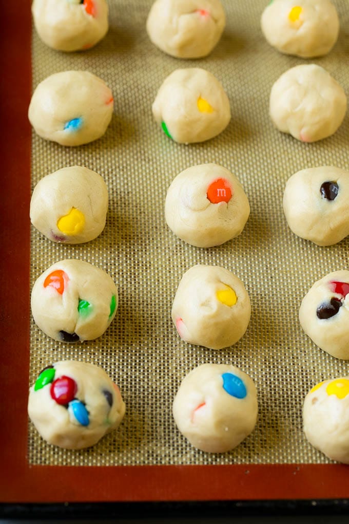 M&M Cookies Recipe #cookies #chocolate #baking #dessert #sweets #jonep Balls of cookie dough on a baking sheet.