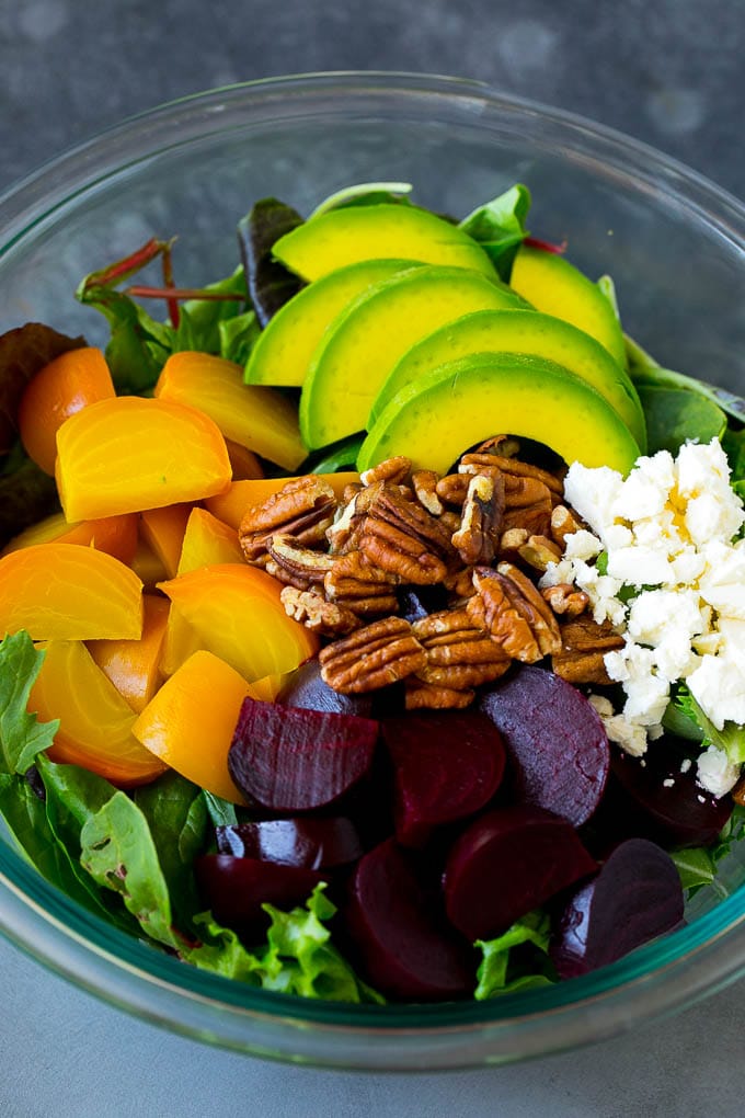 Beet Salad Recipe #beets #avocado #feta #salad #dinner #jonep Red and yellow beets, salad greens, feta cheese, avocado and pecans in a bowl.