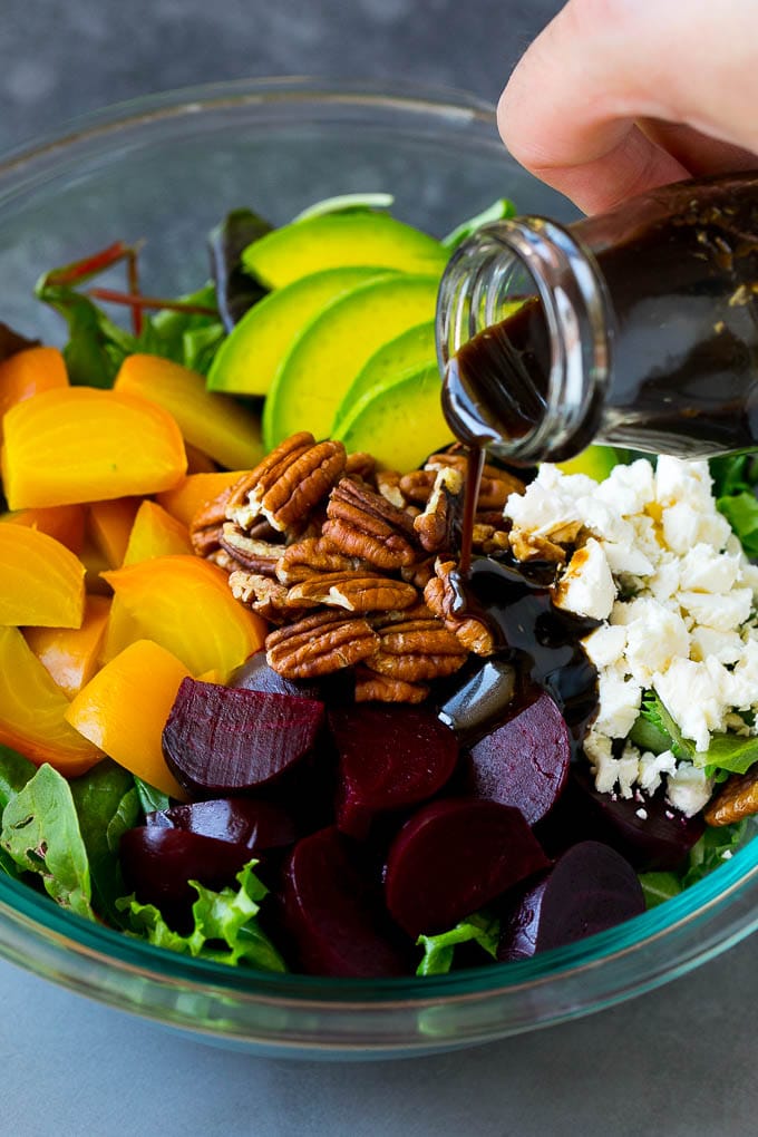 Beet Salad Recipe #beets #avocado #feta #salad #dinner #jonep Balsamic dressing being poured over beets, sliced avocado and feta cheese.