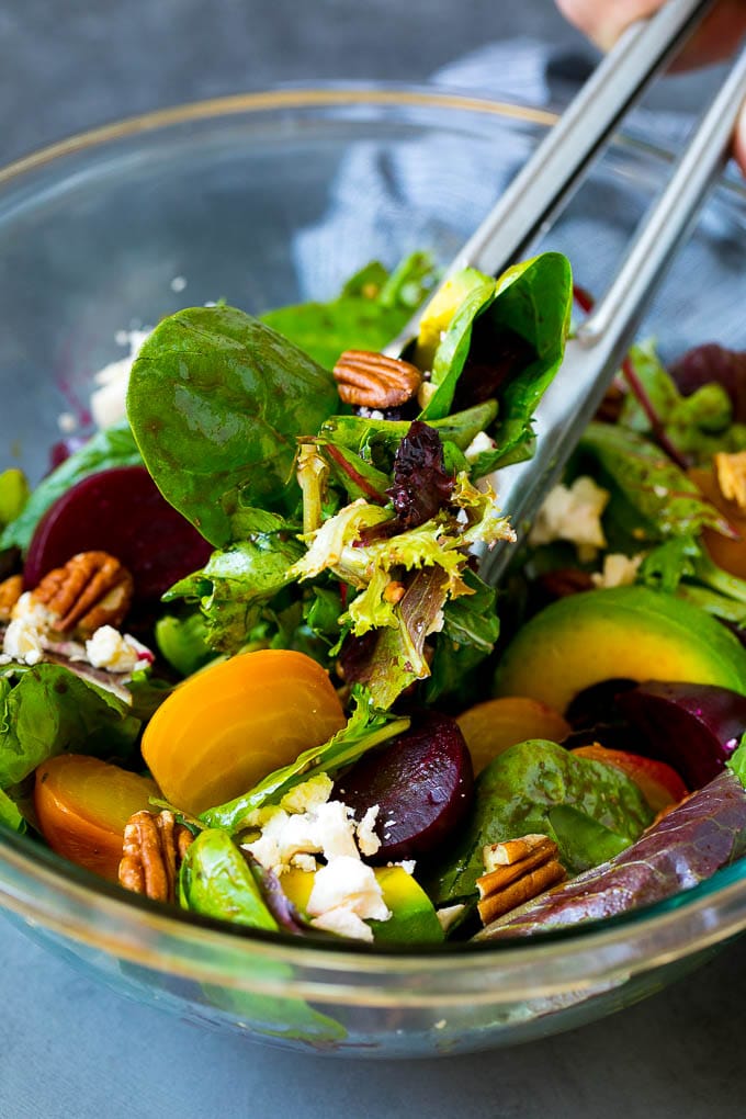 Beet Salad Recipe #beets #avocado #feta #salad #dinner #jonep Tongs serving a portion of beet salad tossed in balsamic dressing.