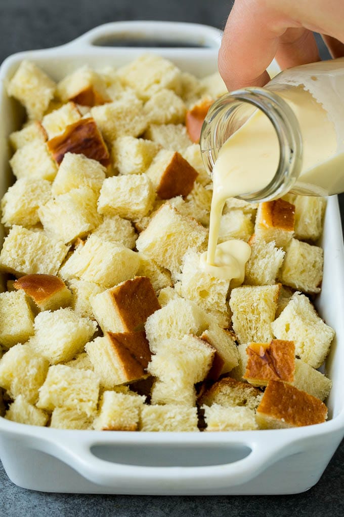 French Toast Casserole Recipe | French Toast Bake #frenchtoast #casserole #breakfast #brunch #jonep #bread A mixture of milk and eggs being poured over cubes of bread.
