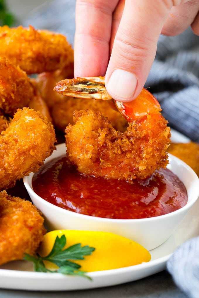 Fried Shrimp Recipe #shrimp #seafood #dinner #appetizer #jonep A hand dipping a shrimp into cocktail sauce.