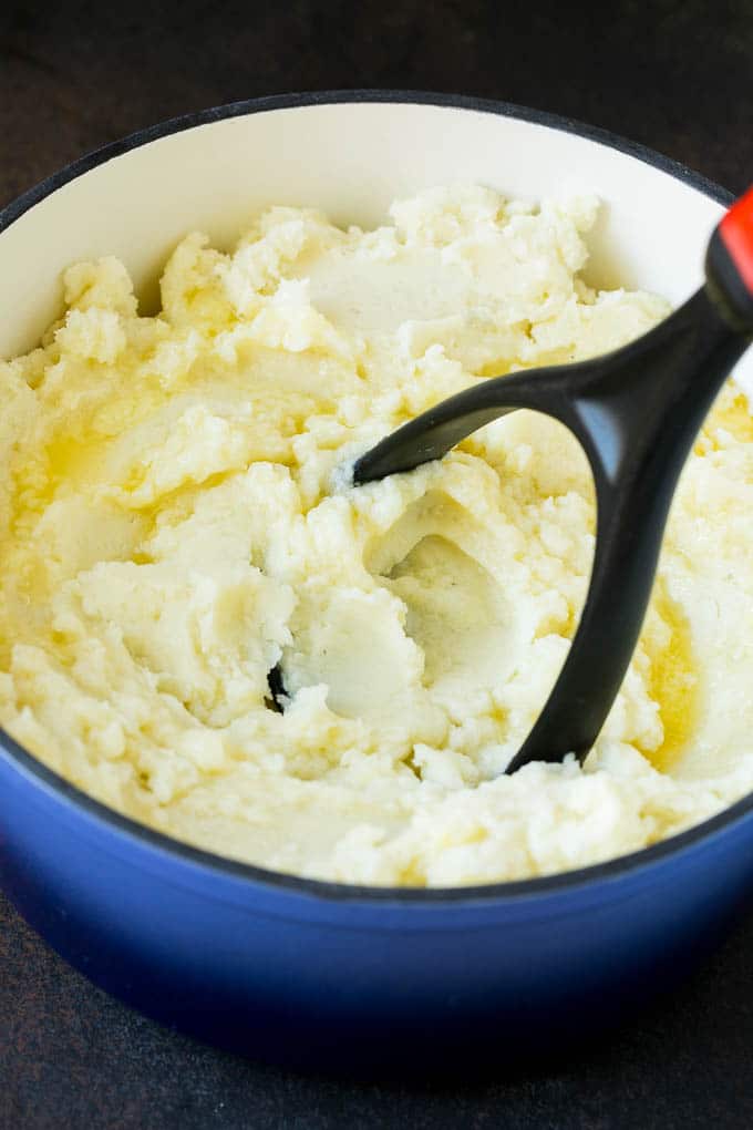 Garlic Mashed Potatoes Recipe #garlic #potatoes #mashedpotatoes #sidedish #dinner #thanksgiving #jonep A potato masher smashing diced cooked potatoes.