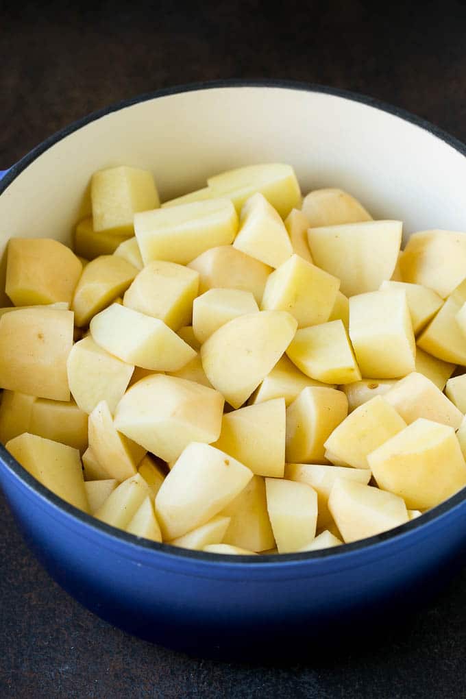 Garlic Mashed Potatoes Recipe #garlic #potatoes #mashedpotatoes #sidedish #dinner #thanksgiving #jonep Diced potatoes in a large blue pot.
