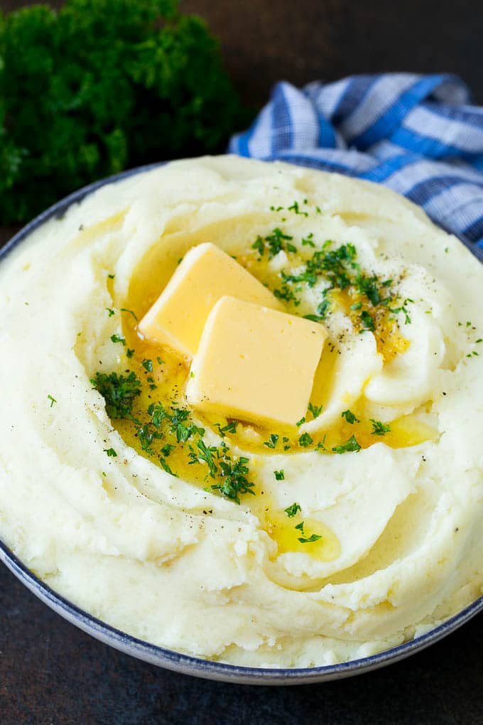 Garlic Mashed Potatoes Recipe #garlic #potatoes #mashedpotatoes #sidedish #dinner #thanksgiving #jonep Garlic mashed potatoes topped with pats of butter and parsley.