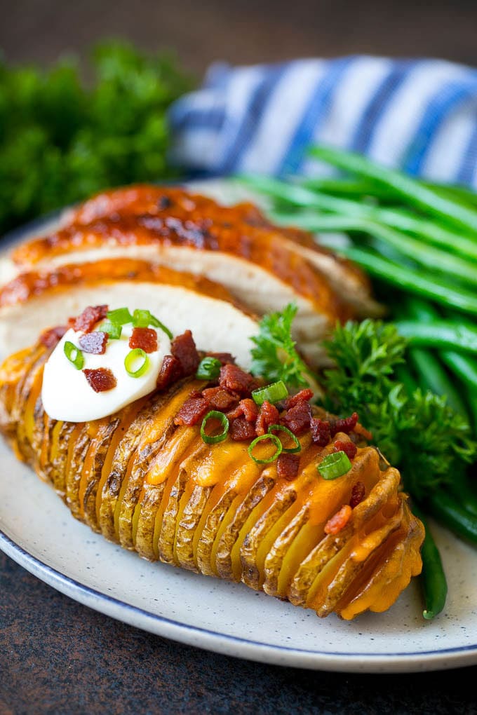 Hasselback Potatoes Recipe #potatoes #bacon #sidedish #cheese #dinner #jonep Hasselback potatoes on a plate, served with turkey and green beans.