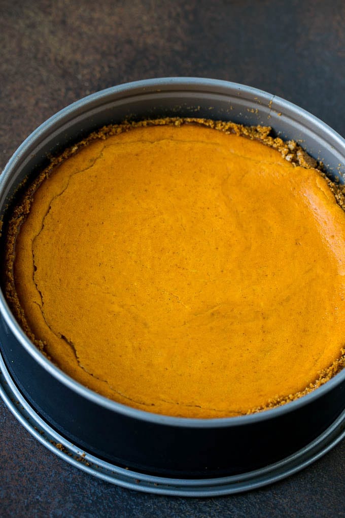 Pumpkin Pie Cheesecake Recipe | Pumpkin Cheesecake #cake #cheesecake #pumpkin #fall #thanksgiving #dessert #jonep A baked pumpkin cheesecake in a pan.