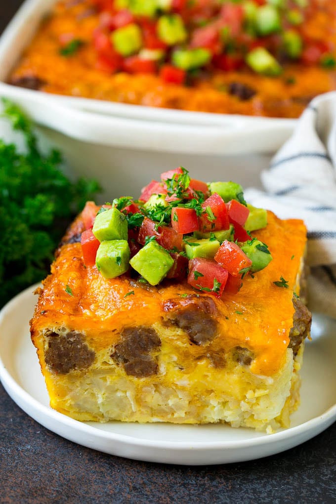 Sausage Egg Casserole Recipe | Egg Casserole #eggs #sausage #potato #cheese #casserole #breakfast #brunch #jonep A slice of sausage egg casserole with a garnish of fresh tomatoes.