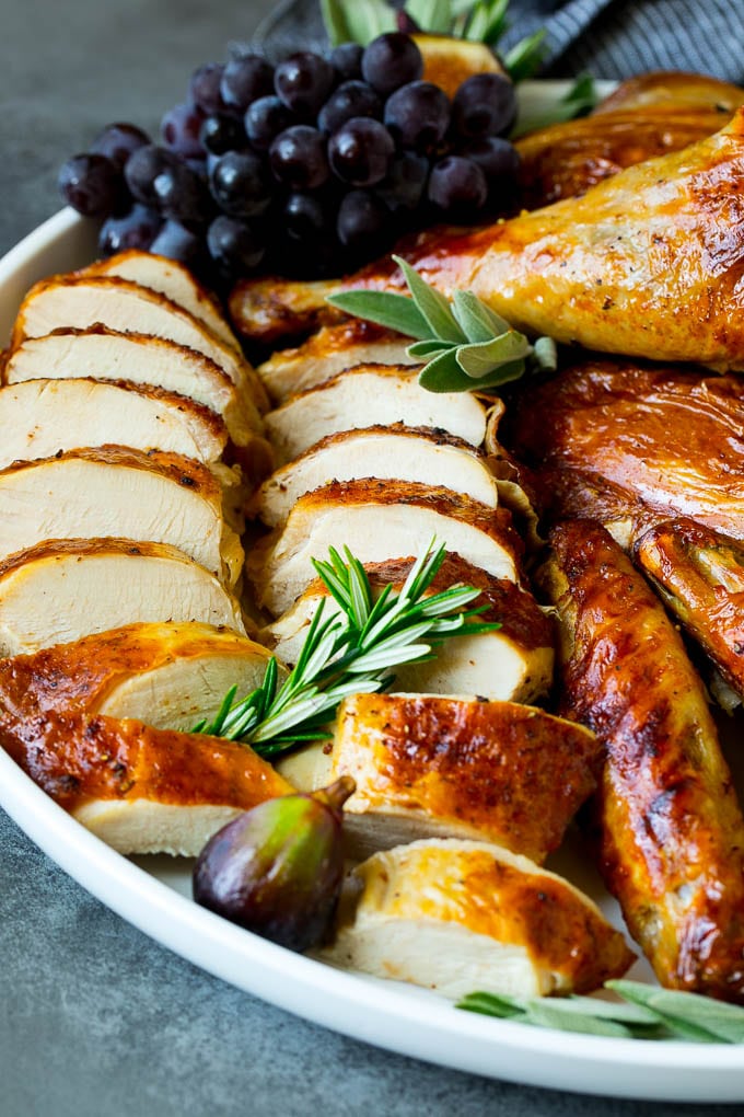 Spatchcock Turkey | Roasted Turkey | Thanksgiving Turkey #turkey #thanksgiving #dinner #fall #christmas #jonep Sliced spatchcock turkey on a serving platter garnished with herbs.
