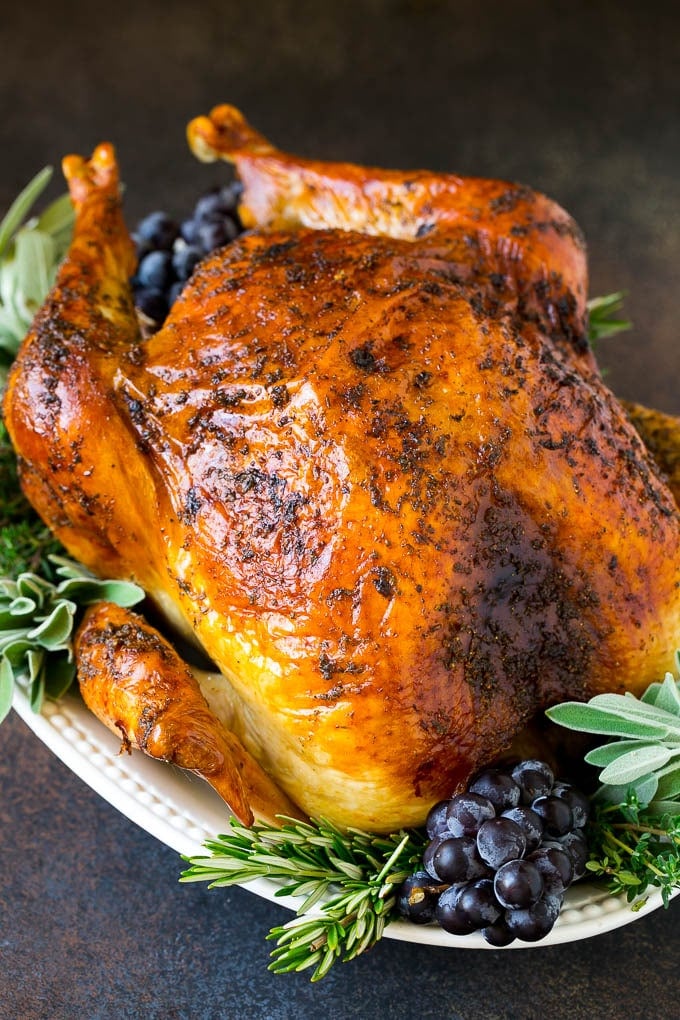 Thanksgiving Turkey Recipe | Roasted Turkey #turkey #thanksgiving #fall #dinner #jonep A whole roasted Thanksgiving turkey on a platter that's decorated with grapes and herbs.