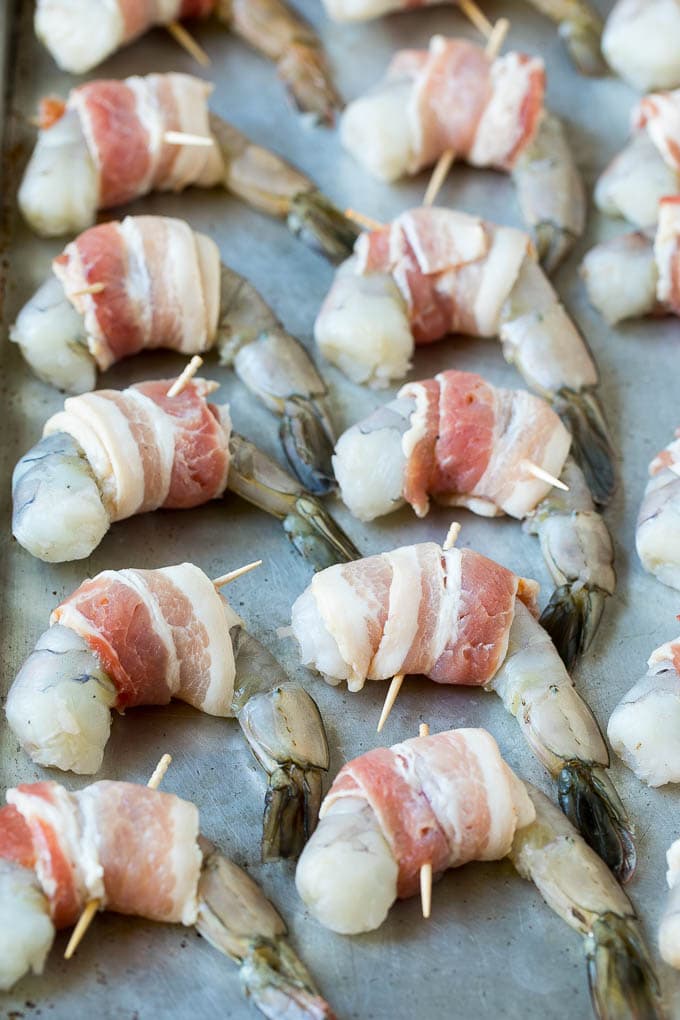 Bacon Wrapped Shrimp Recipe | Bacon Shrimp #shrimp #bacon #appetizer #dinner #jonep #seafood Raw seafood on a sheet pan wrapped in pork.