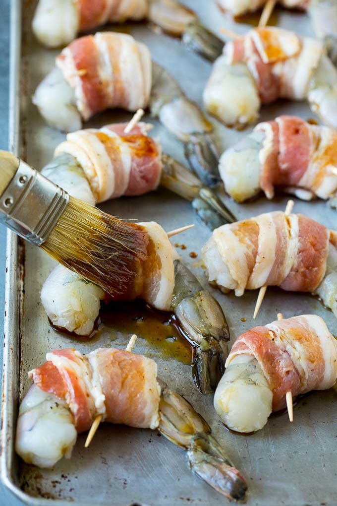 Bacon Wrapped Shrimp Recipe | Bacon Shrimp #shrimp #bacon #appetizer #dinner #jonep #seafood A basting brush applying sauce to shrimp.