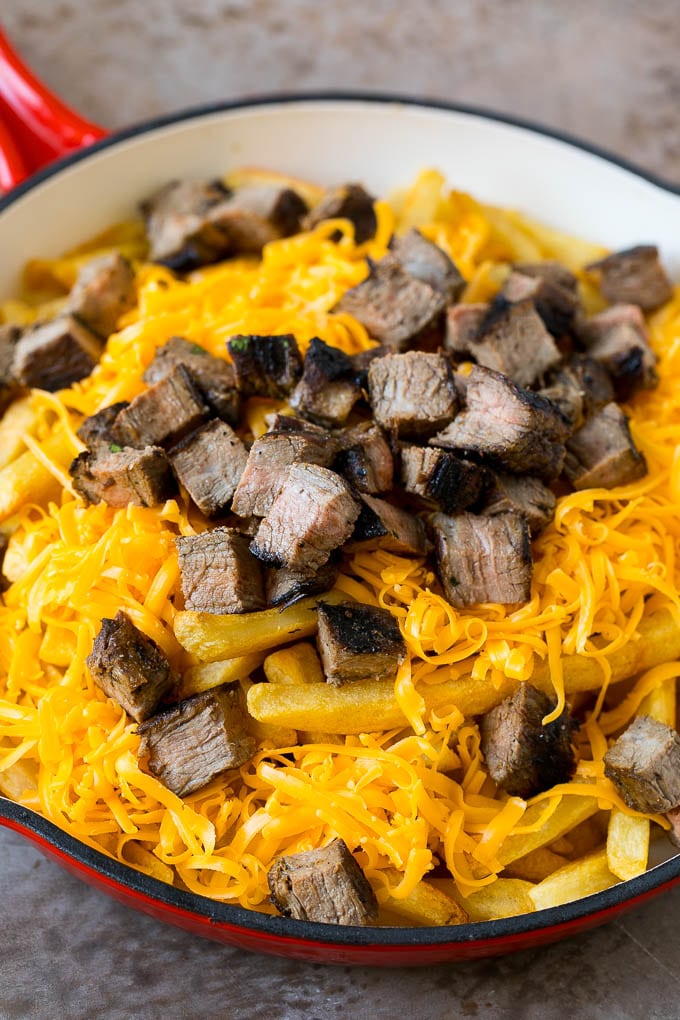 Carne Asada Fries Recipe | Steak Fries #fries #frenchfries #steak #salsa #avocado #cheese #dinner #appetizer #jonep French fries topped with shredded cheese and diced steak.