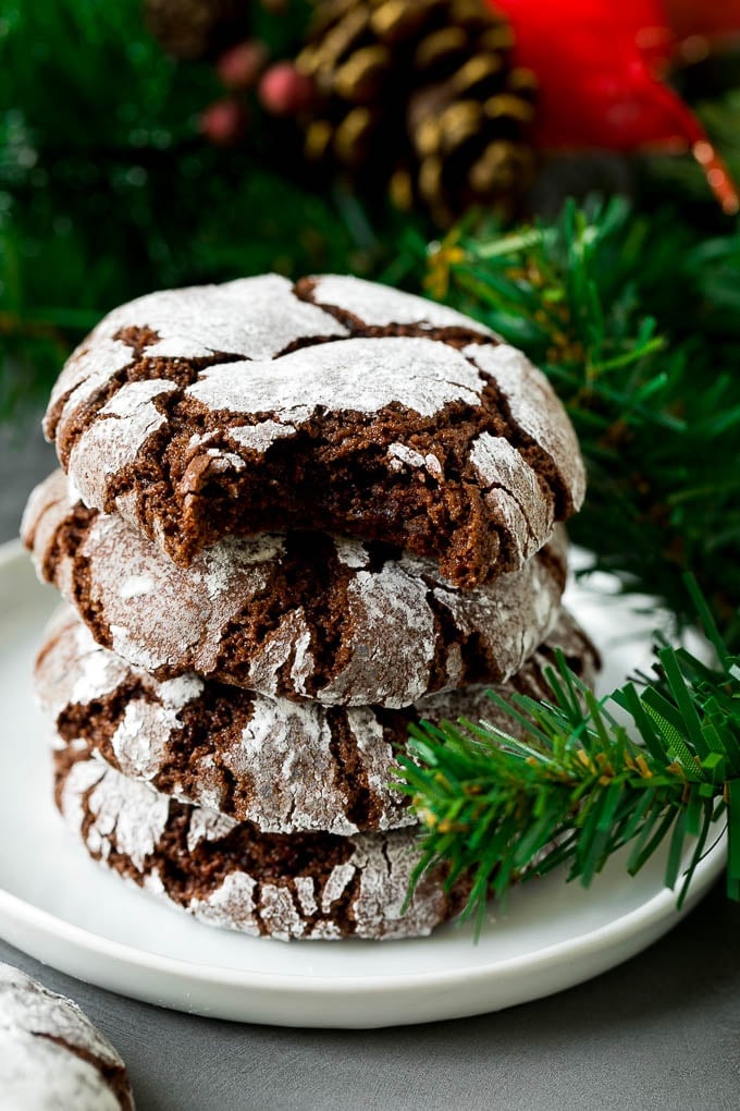 Chocolate Crinkle Cookies Recipe #cookies #chocolate #christmas #dessert #baking #jonep A stack of chocolate crinkle cookies with a bite taken out of one.