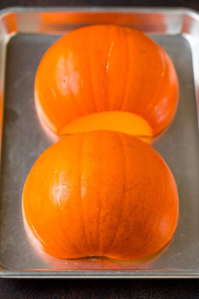 Pumpkin Puree Recipe #pumpkin #baking #fall #thanksgiving #jonep A pumpkin cut in half on a sheet pan.