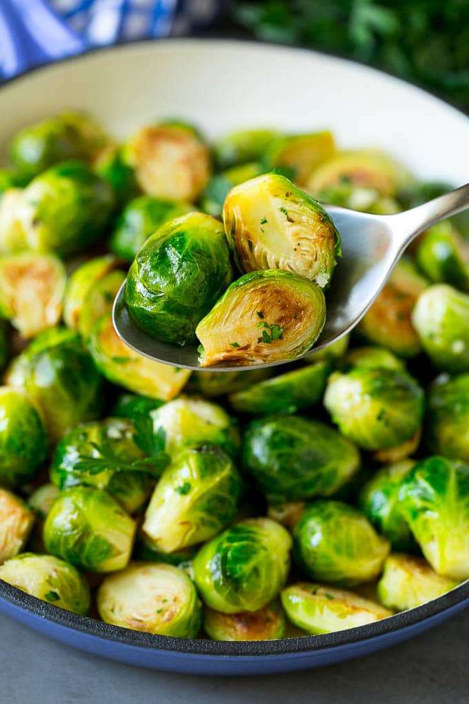 Sauteed Brussels Sprouts Recipe | Brussels Sprouts Side Dish #brusselssprouts #sprouts #veggies #sidedish #garlic #vegetarian #dinner #jonep A spoon holding up a serving of cooked brussels sprouts.