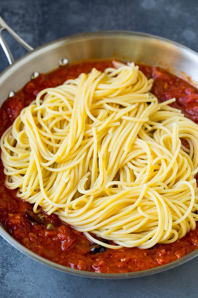 Pasta Puttanesca Recipe #pasta #tomatoes #olives #italianfood #dinner #jonep Spaghetti in a pan of tomato sauce with olives and capers.