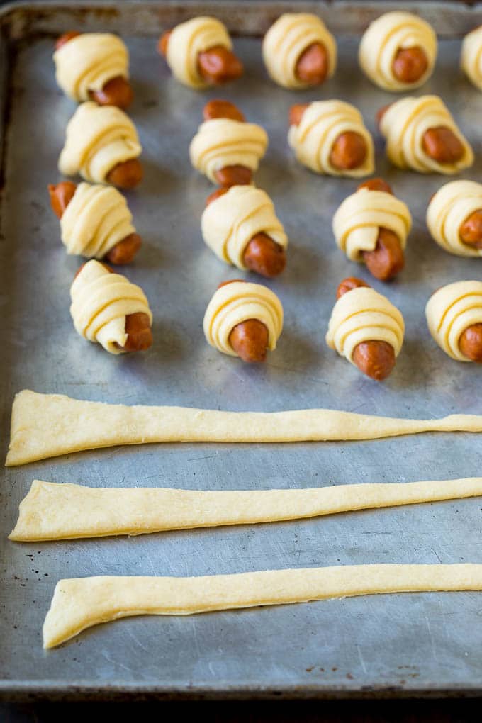 Pigs in a Blanket Recipe #hotdogs #appetizer #snack #comfortfood #jonep Strips of crescent dough on a sheet pan.