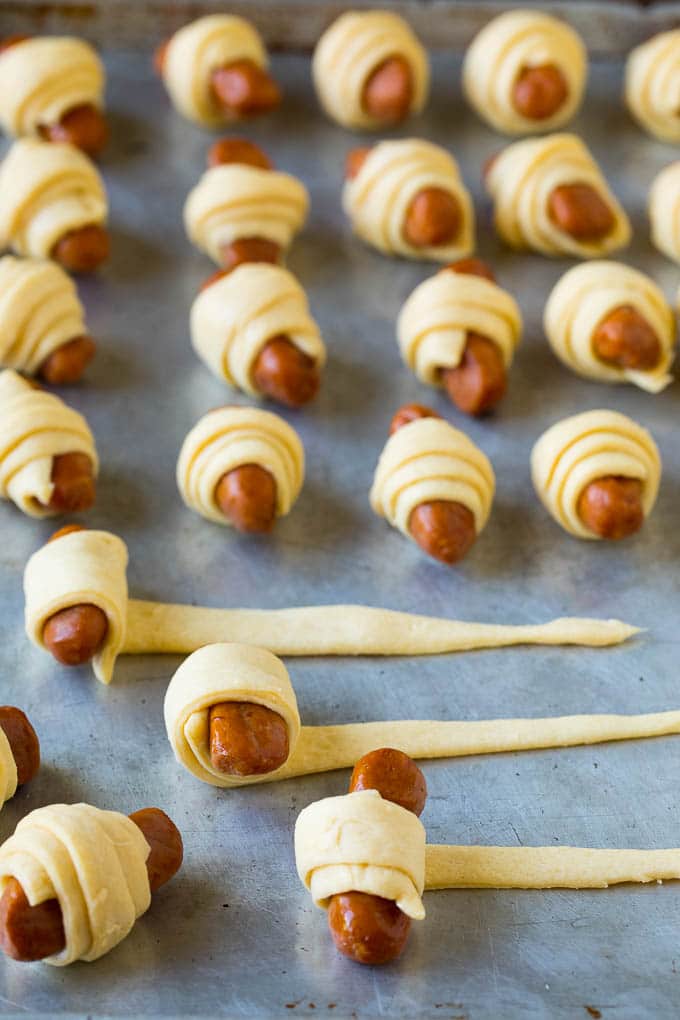 Pigs in a Blanket Recipe #hotdogs #appetizer #snack #comfortfood #jonep Hot dogs being rolled up in dough.