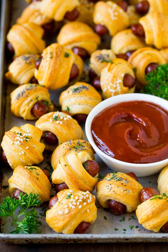 Pigs in a Blanket Recipe #hotdogs #appetizer #snack #comfortfood #jonep A sheet pan of pigs in a blanket, garnished with parsley and served with ketchup.