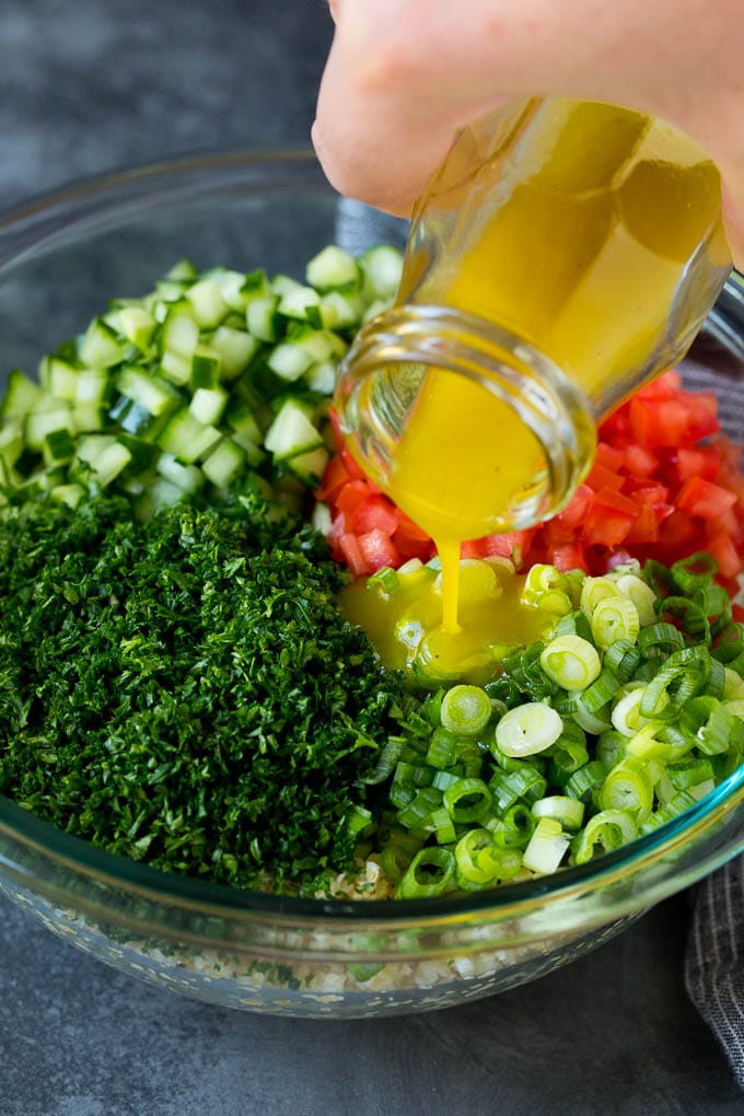 Tabbouleh Salad | Tabouli #salad #wheat #tomatoes #cucumber #healthy #sidedish #dinner #jonep Dressing being poured into a bowl of bulgur wheat salad.