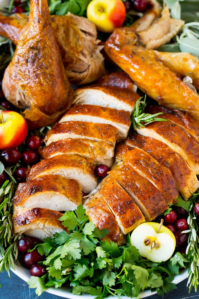 This dry brined turkey is coated in a blend of salt, herbs and spices, then roasted to golden brown perfection. Dry brined turkey sliced and served on a platter with herbs.
