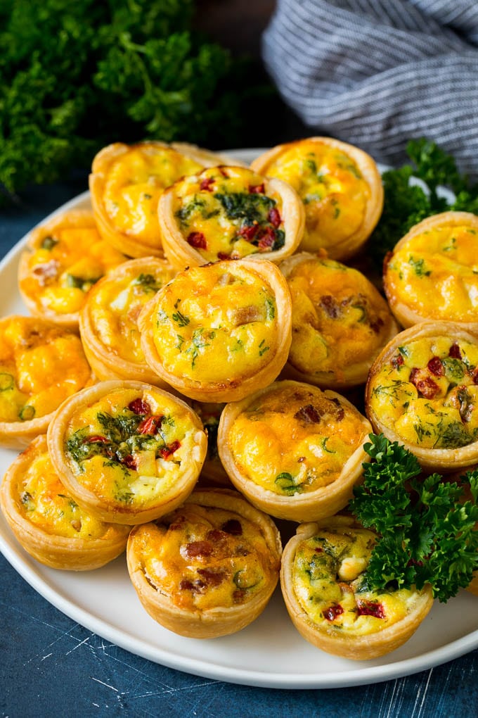 Mini Quiche Recipe #eggs #breakfast #brunch #appetizer #jonep A plate of mini quiche filled with meats, vegetables and cheeses.