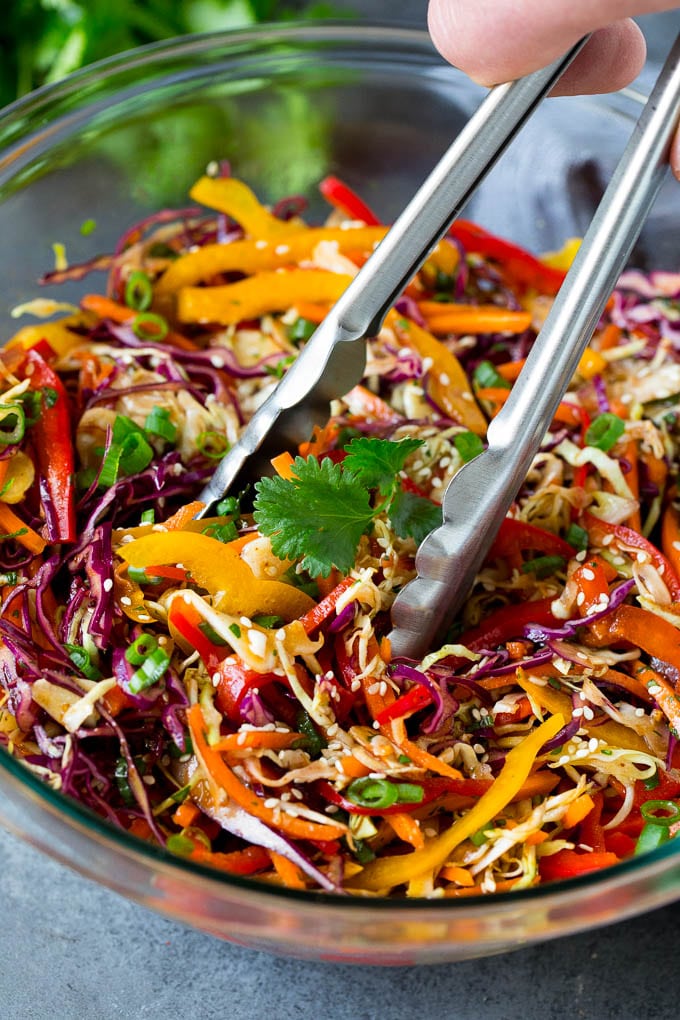 Asian Slaw Recipe #salad #slaw #sidedish #jonep Tongs serving up a portion of Asian slaw.