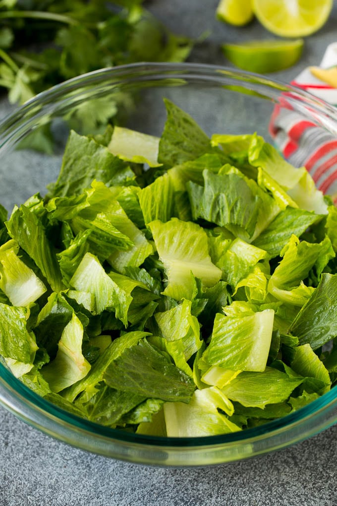 Mexican Salad Recipe #salad #corn #beans #avocado #tomatoes #jonep Chopped romaine lettuce in a bowl.