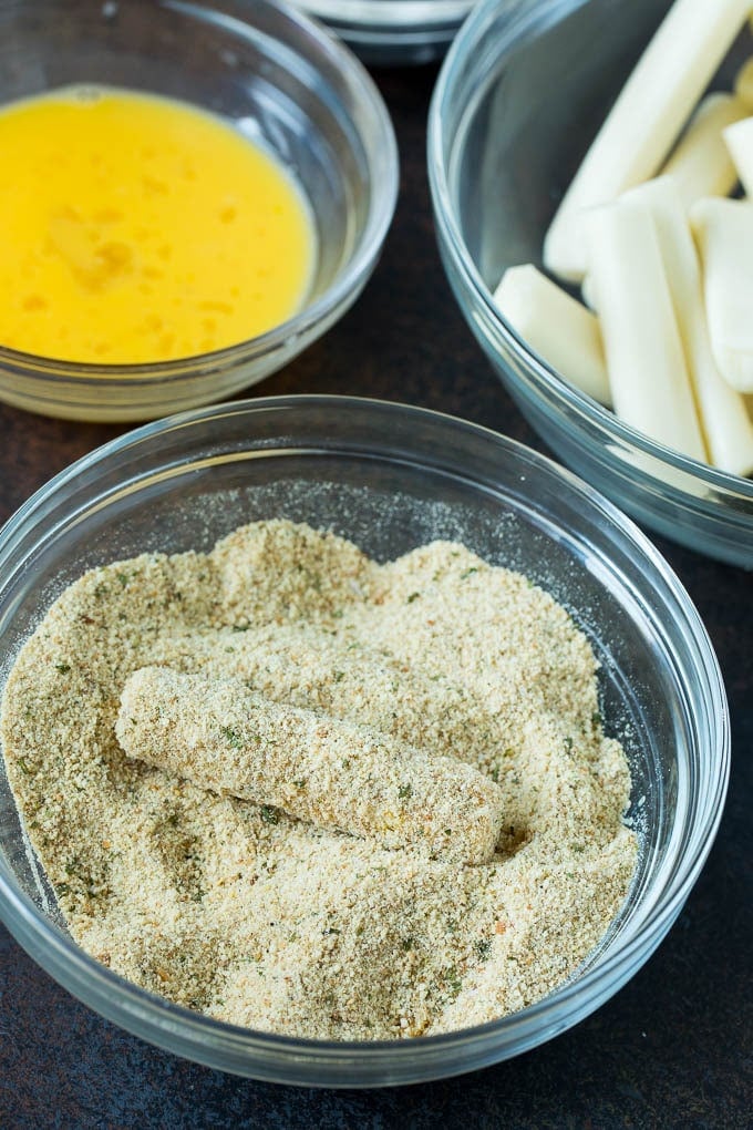 Mozzarella Sticks Recipe #cheese #appetizer #jonep Cheese in a bowl of seasoned breadcrumbs.