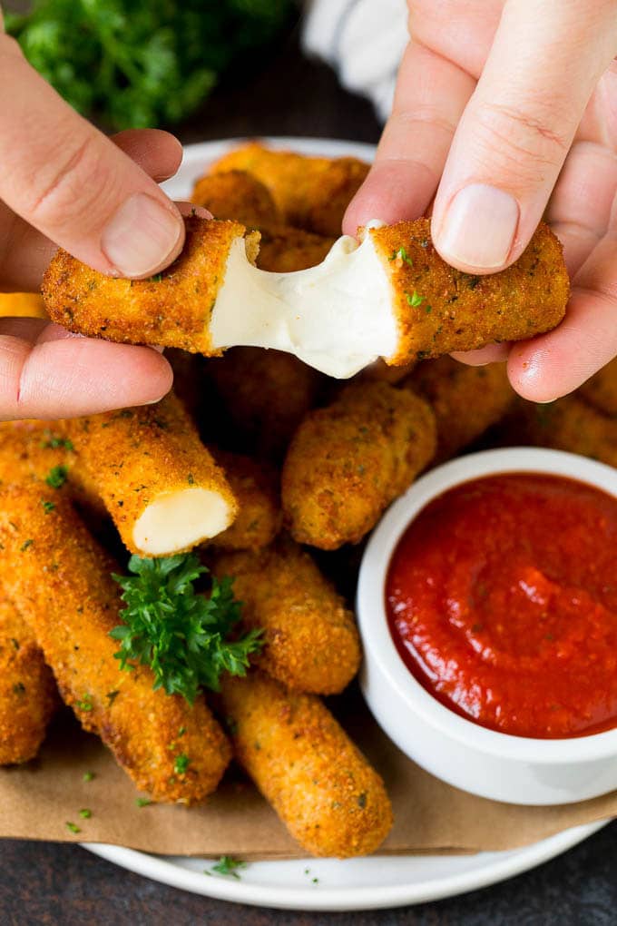 Mozzarella Sticks Recipe #cheese #appetizer #jonep A hand pulling apart mozzarella sticks.