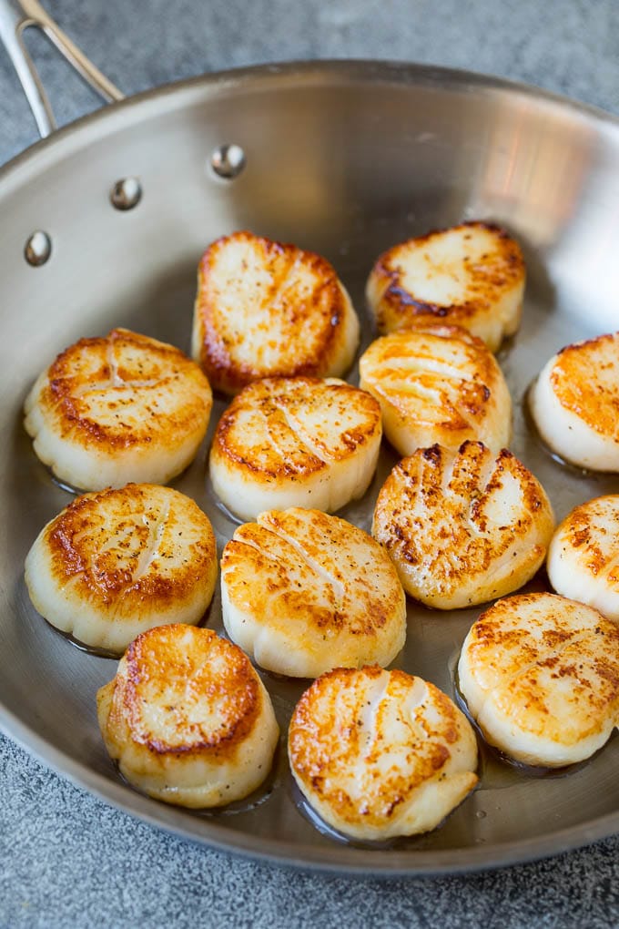 Seared scallops with a garlic and herb butter sauce. An easy and elegant dinner! #seafood #dinner #jonep Scallops cooked to golden brown in a pan.