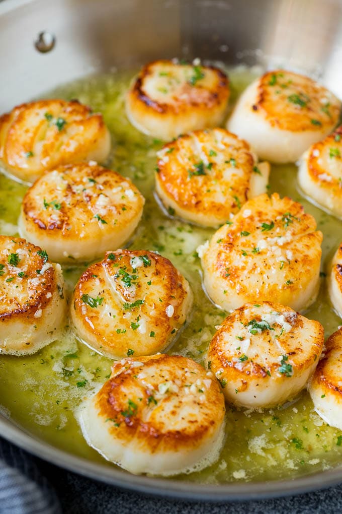 Seared scallops with a garlic and herb butter sauce. An easy and elegant dinner! #seafood #dinner #jonep A pan of scallops in garlic butter.