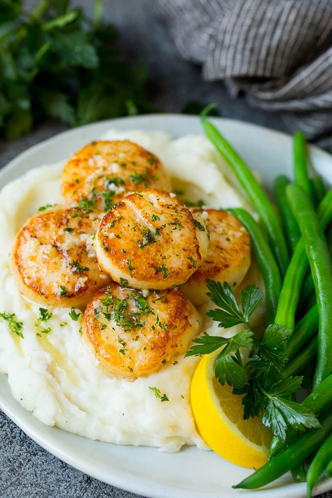 Seared scallops with a garlic and herb butter sauce. An easy and elegant dinner! #seafood #dinner #jonep Seared scallops served with mashed potatoes and green beans.