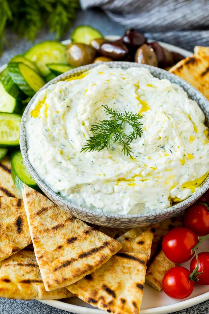 The best homemade tzatziki sauce with cucumber and herbs mixed into Greek yogurt. #appetizer #jonep A bowl of tzatziki served with pita bread and vegetables.