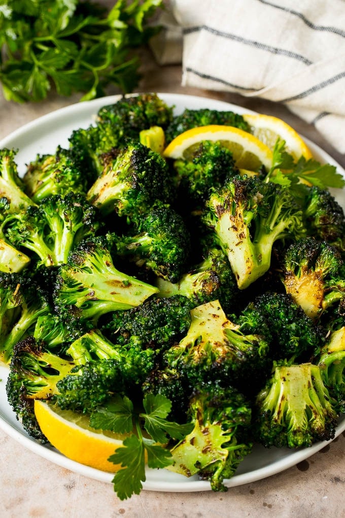 Grilled broccoli is packed with flavor and is a colorful and healthy side dish! #broccoli #jonep Grilled broccoli topped with parsley and garnished with lemon wedges.