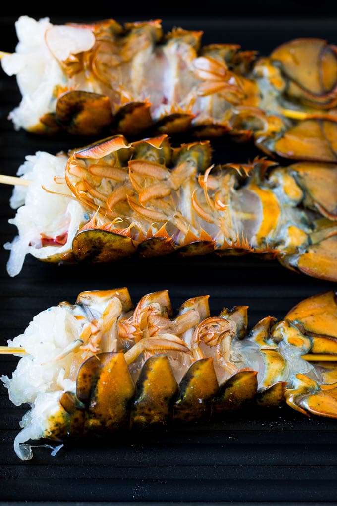 Grilled lobster tail drizzled with garlic butter is an easy and elegant dinner option. #lobster #jonep Lobster tails upside down on a grill pan.