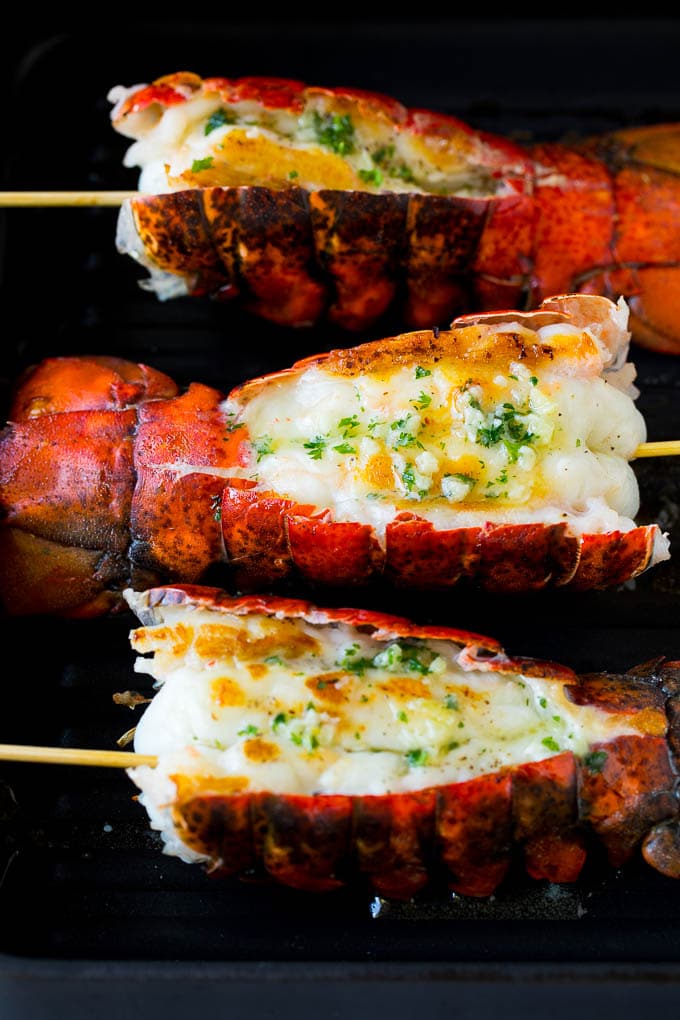 Grilled lobster tail drizzled with garlic butter is an easy and elegant dinner option. #lobster #jonep Cooked lobster tails on a grill pan, brushed with butter.