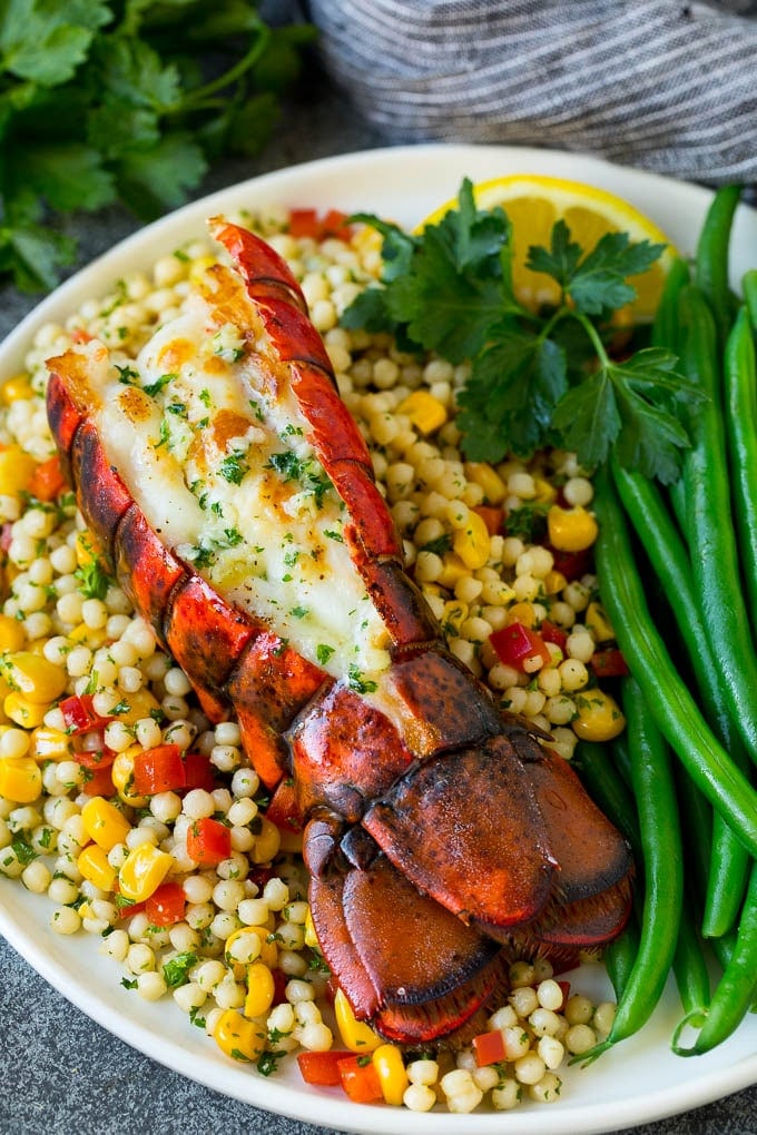 Grilled lobster tail drizzled with garlic butter is an easy and elegant dinner option. #lobster #jonep Grilled lobster tail served with couscous and green beans.