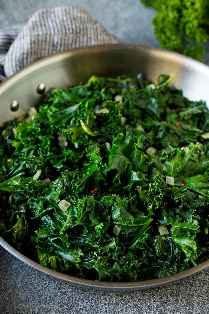 Sauteed kale flavored with olive oil and garlic, a quick and easy side dish! #kale #jonep Cooked kale with olive oil, onions and garlic.