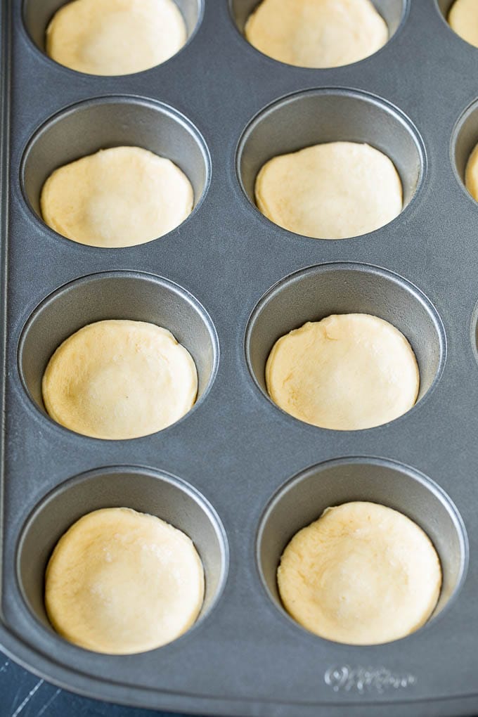 Mini pizzas topped with pepperoni are a fun and easy appetizer option. #pizza #jonep #appetizer Dough circles pressed into muffin cups.