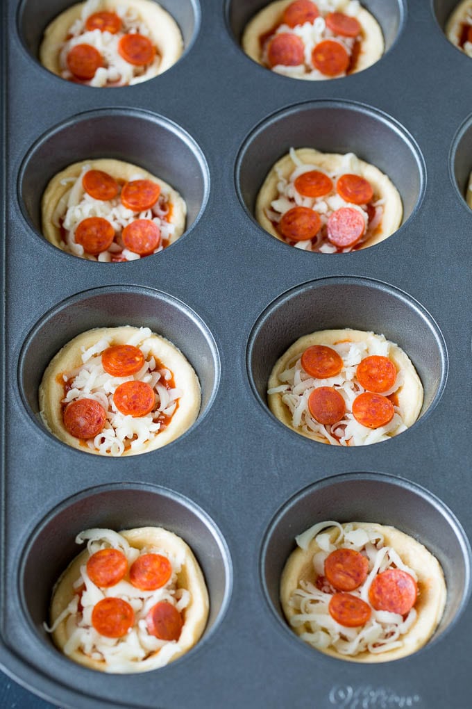 Mini pizzas topped with pepperoni are a fun and easy appetizer option. #pizza #jonep #appetizer Dough topped with sauce, cheese and mini pepperoni.