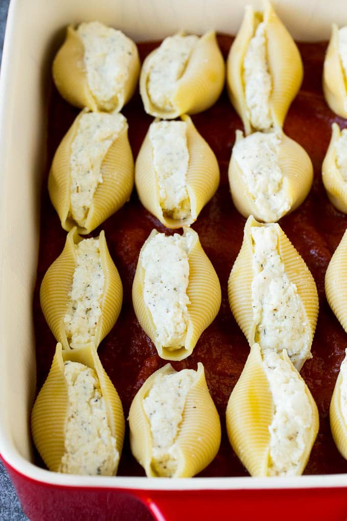 Baked stuffed shells filled with three types of cheese and topped with marinara sauce. #pasta #jonep Pasta filled with cheese on a bed of tomato sauce.