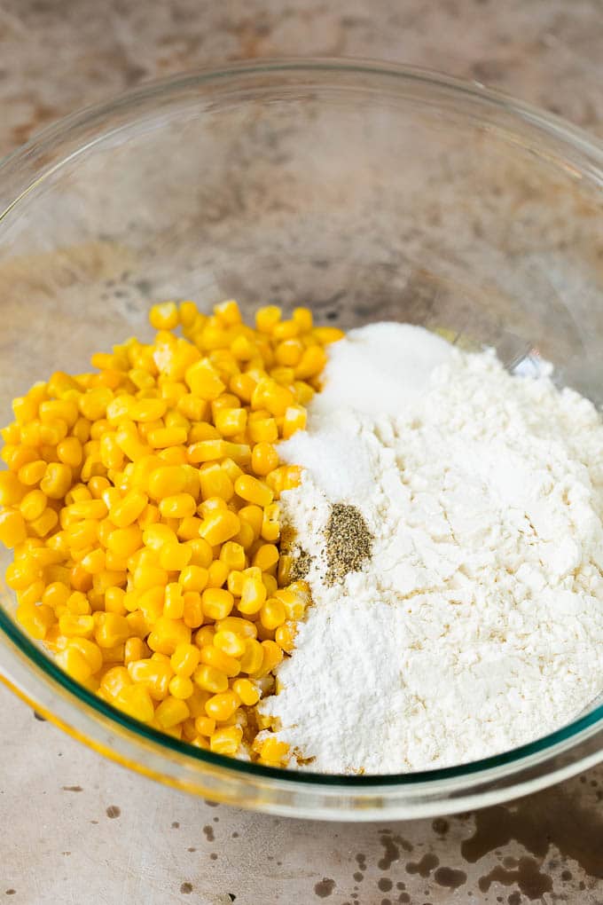These crispy corn fritters are easy to make and are the perfect appetizer or lighter main course. #corn #jonep Flour, corn and seasonings in a mixing bowl.
