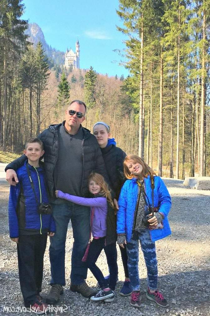 Neuschwanstein is 'n ongelooflike sprokieskasteel in Hohenschwangau, Beiere, Duitsland en is so 'n magiese plek vir kinders en volwassenes ook. Hier is wat jy moet weet oor die besoek van Neuschwanstein met kinders op jou Europese Gesinsvakansie. Vier kinders en hul pa wat op die pad na Neuschwanstein staan.