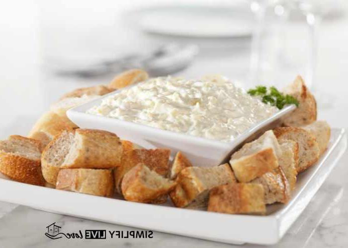 **Συνταγή Μακαρονοσαλάτας με Παρμεζάνα, Ασιάγκο και Ελιές** 3 parmesan asiago spread on a white plate with crusty bread
