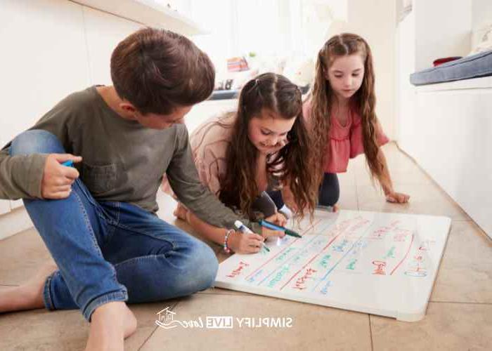 kids on floor with whiteboard making daily routine for cleaning