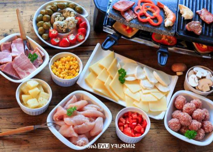 Raclette-braaier vir 'n aandete partytjie met vleise en groente in klein wit bakkies rondom die braaier