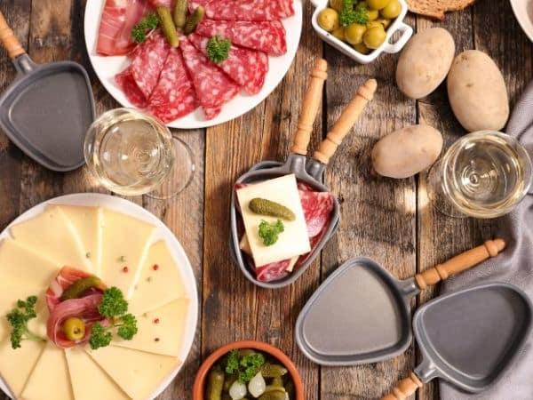 Mense wat Raclette kaas smelt by 'n tafel vir 'n Raclette aandete.