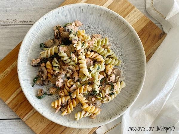 Kaasagtige Salm Pasta met Spinasie en Sampioene 7 salmon pasta with mushrooms and spinach finished and ready to serve on wooden counter with white cloth napkin